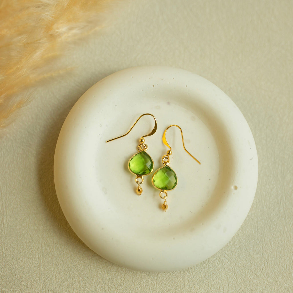 Peridot Ballet Drops with faceted green gemstones, gold hooks and small gold accents, shown as a pair.