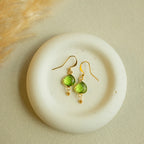 Peridot Ballet Drops with faceted green gemstones, gold hooks and small gold accents, shown as a pair.
