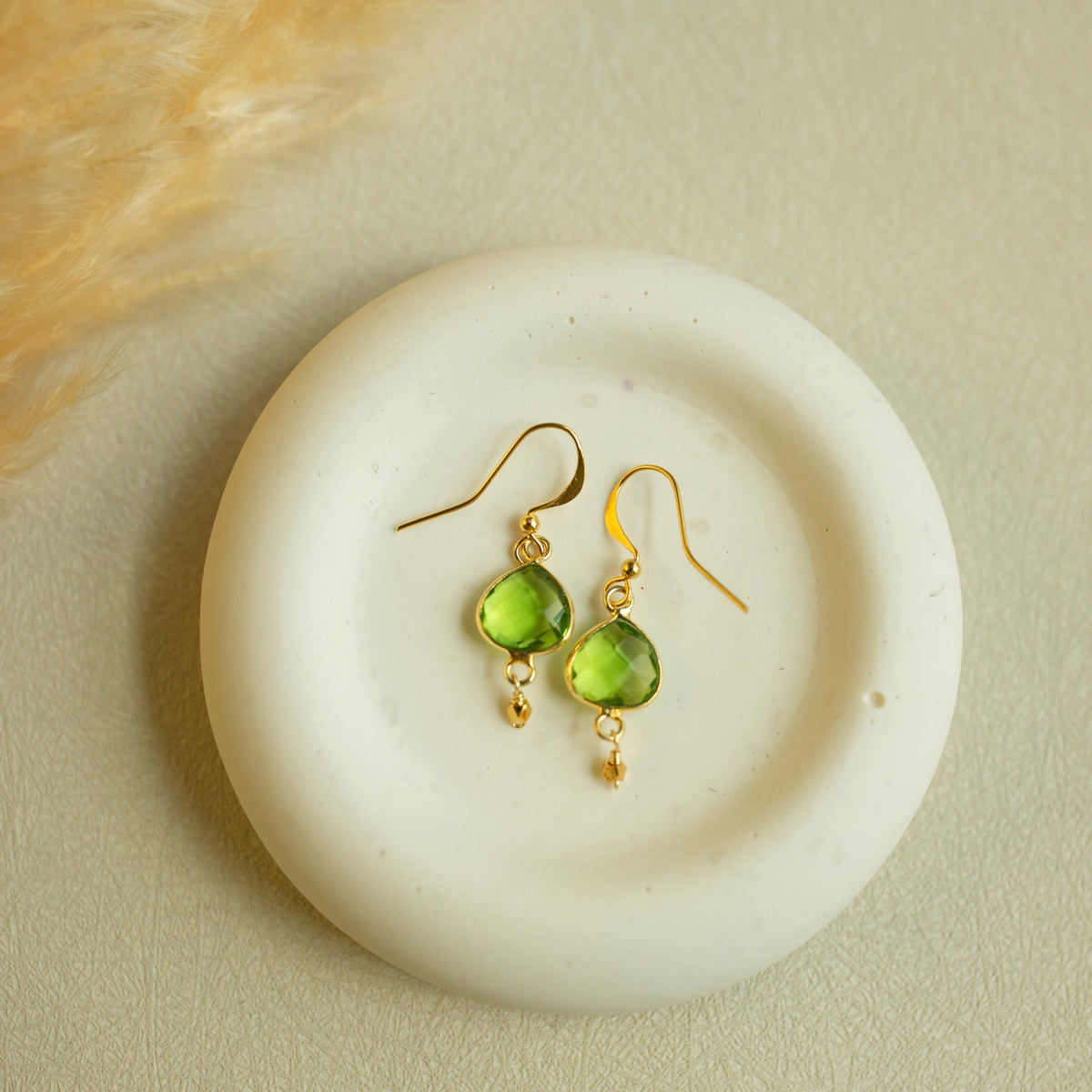 Peridot Ballet Drops with faceted green gemstones, gold hooks and small gold accents, shown as a pair.