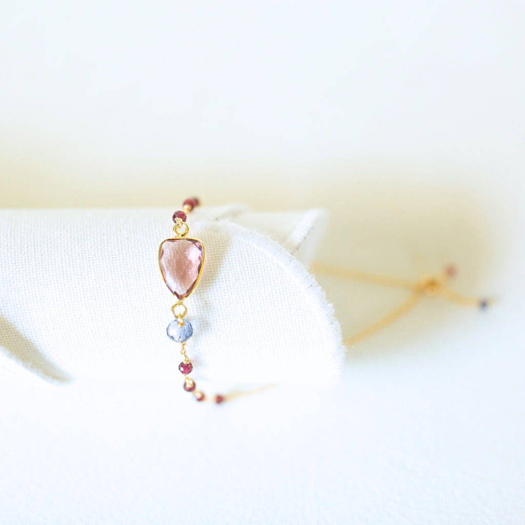 Pink gemstone Isla bracelet with gold-tone links and small bead accents on a white display.