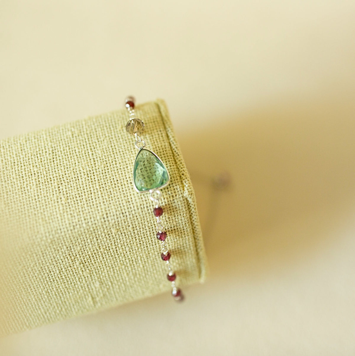 Pale green gemstone Isla bracelet with silver-tone links on a fabric display.