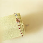 Pink gemstone Isla bracelet with silver-tone links on a fabric display.