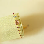 Angled view of a pink gemstone Isla bracelet and bead details on a fabric display.