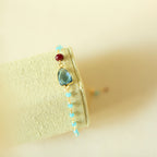Blue gemstone Isla bracelet with gold-tone links on a fabric display.