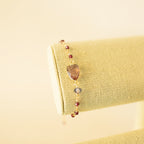 Pink gemstone Isla bracelet with gold-tone links on a fabric display.
