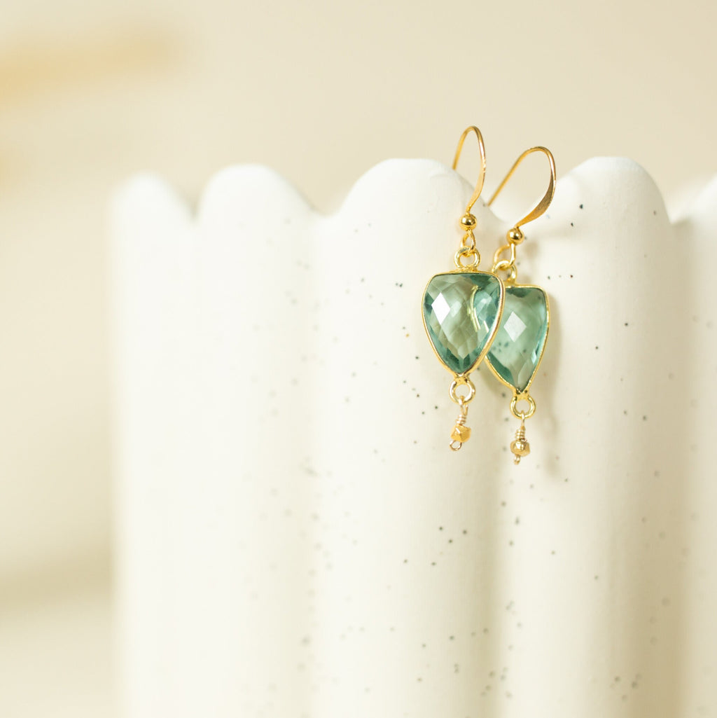 Pale green gemstone Isla Drops with gold-tone hooks on a cream display.