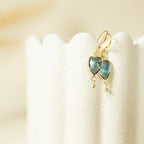 Isla Drops with blue faceted gemstones and gold-tone hooks on a cream display.