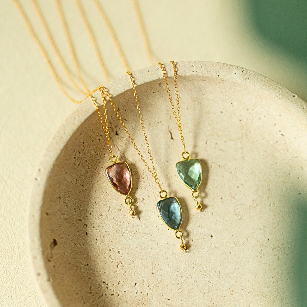 Isla pendant necklaces with pink, blue and green stones on gold-tone chains.