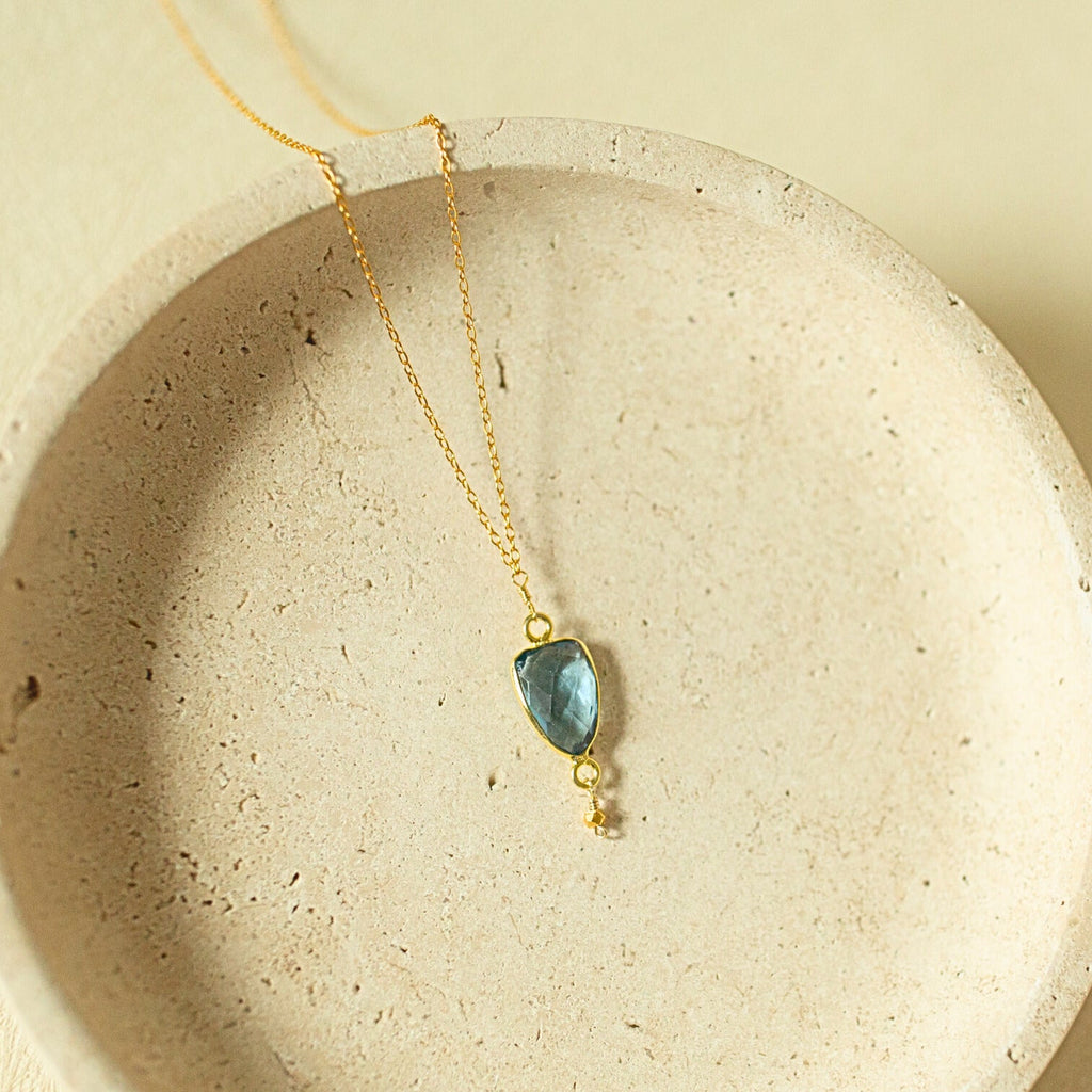 Blue faceted Isla pendant with a small drop detail on a gold-tone chain.