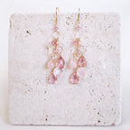The Rosaline Drops with pink and pale gemstone drops and open gold circular links, shown on pale stone.