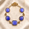 Blue agate stones in mixed shapes connected by ornate golden brass links