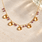 The Citrine Necklace with five golden faceted drops and purple bead accents on a fine gold chain. AI-styled closeup; original photographs remain in the gallery.