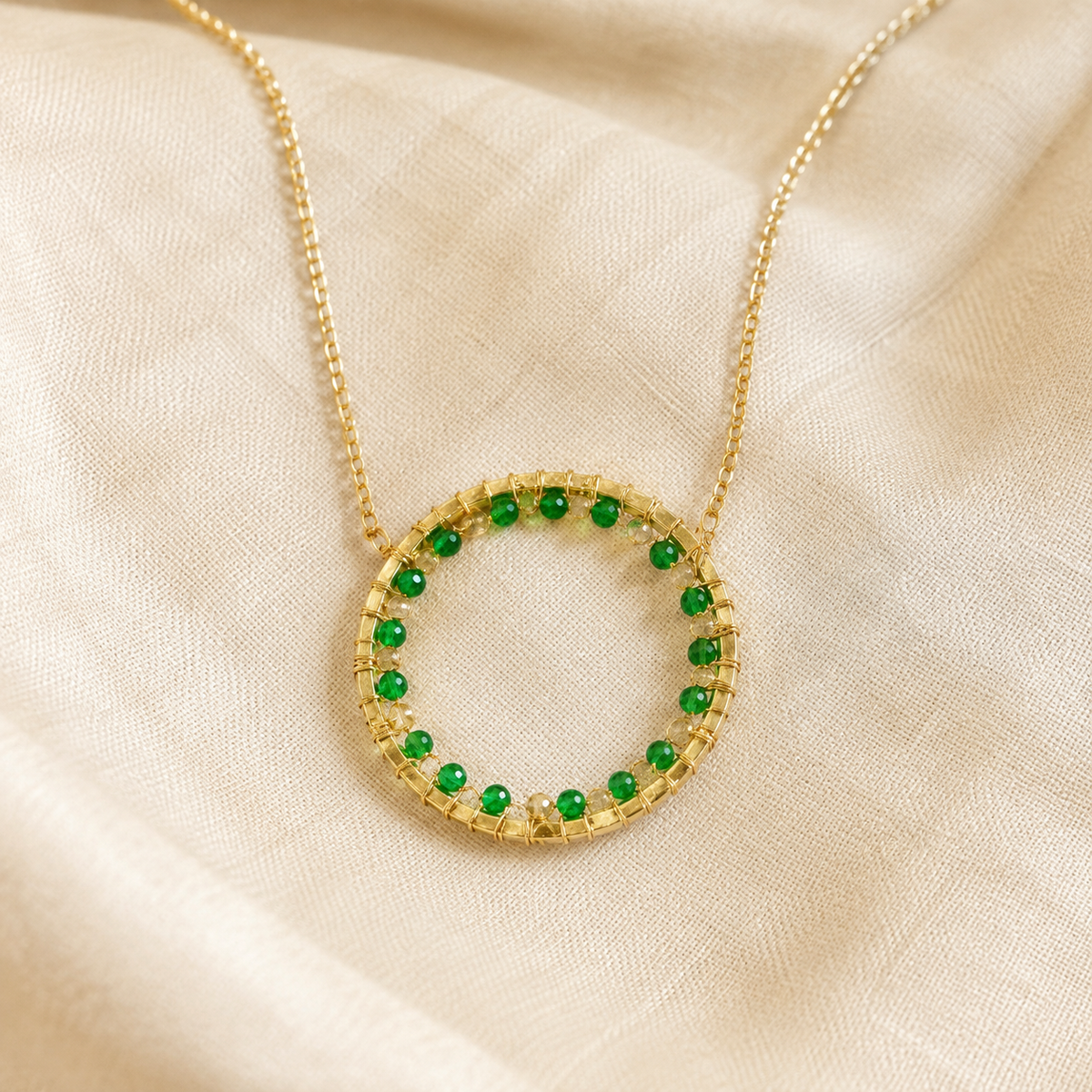 Open golden halo pendant with green gemstone bead details on a fine chain