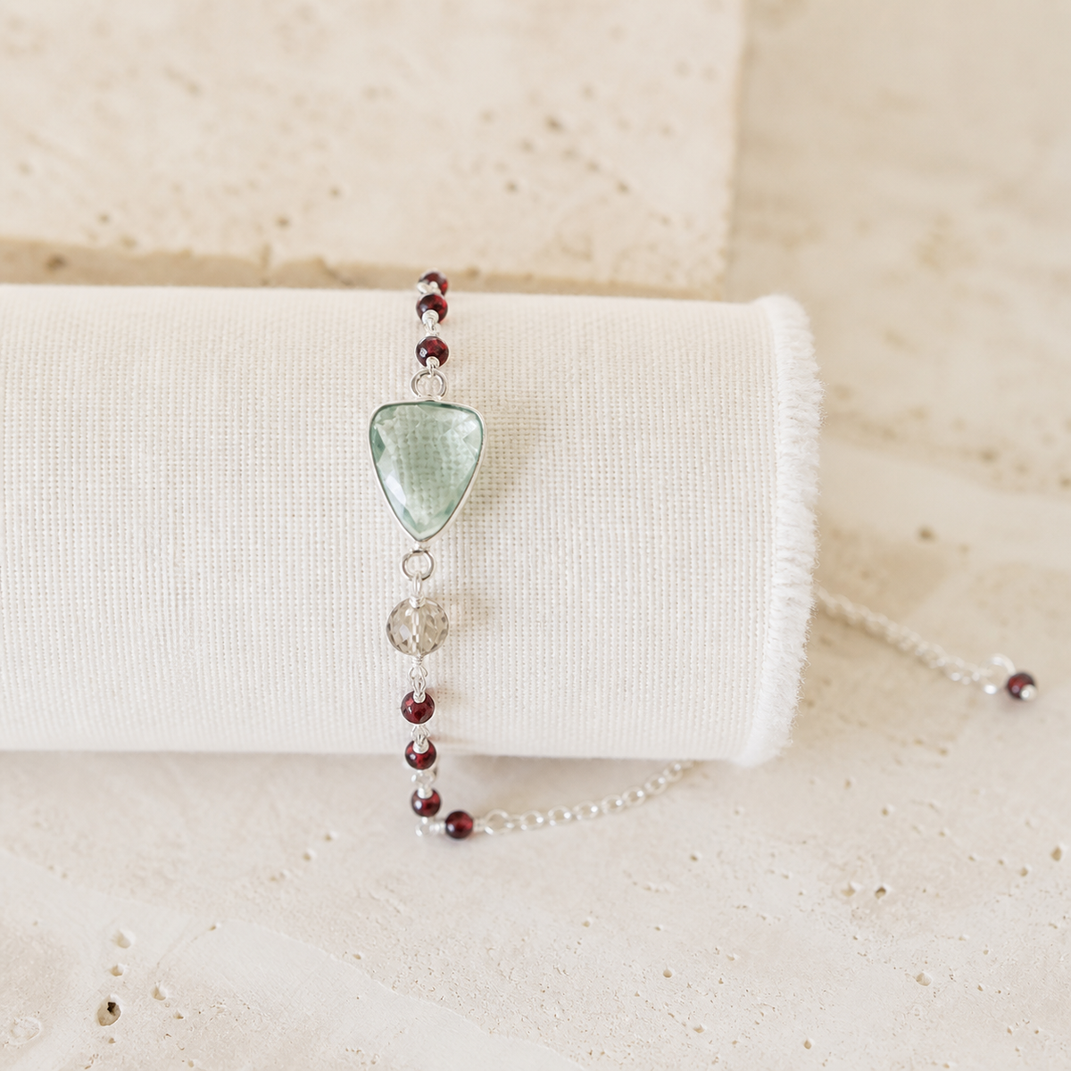 The Isla Bracelet in Green Amethyst and rhodium-plated silver, with red bead details on ivory linen