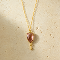 The Isla Pendant in Rhodolite Garnet and gold-plated silver on ivory limestone