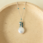 Marea Pendant in London Blue Quartz and rhodium-plated silver, with a freshwater coin pearl on an ivory stone dish; AI-edited from the original product photograph.