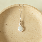 Marea Pendant with small white pearls, rhodium-plated silver and a freshwater coin pearl on an ivory stone dish; AI-edited from the original product photograph.