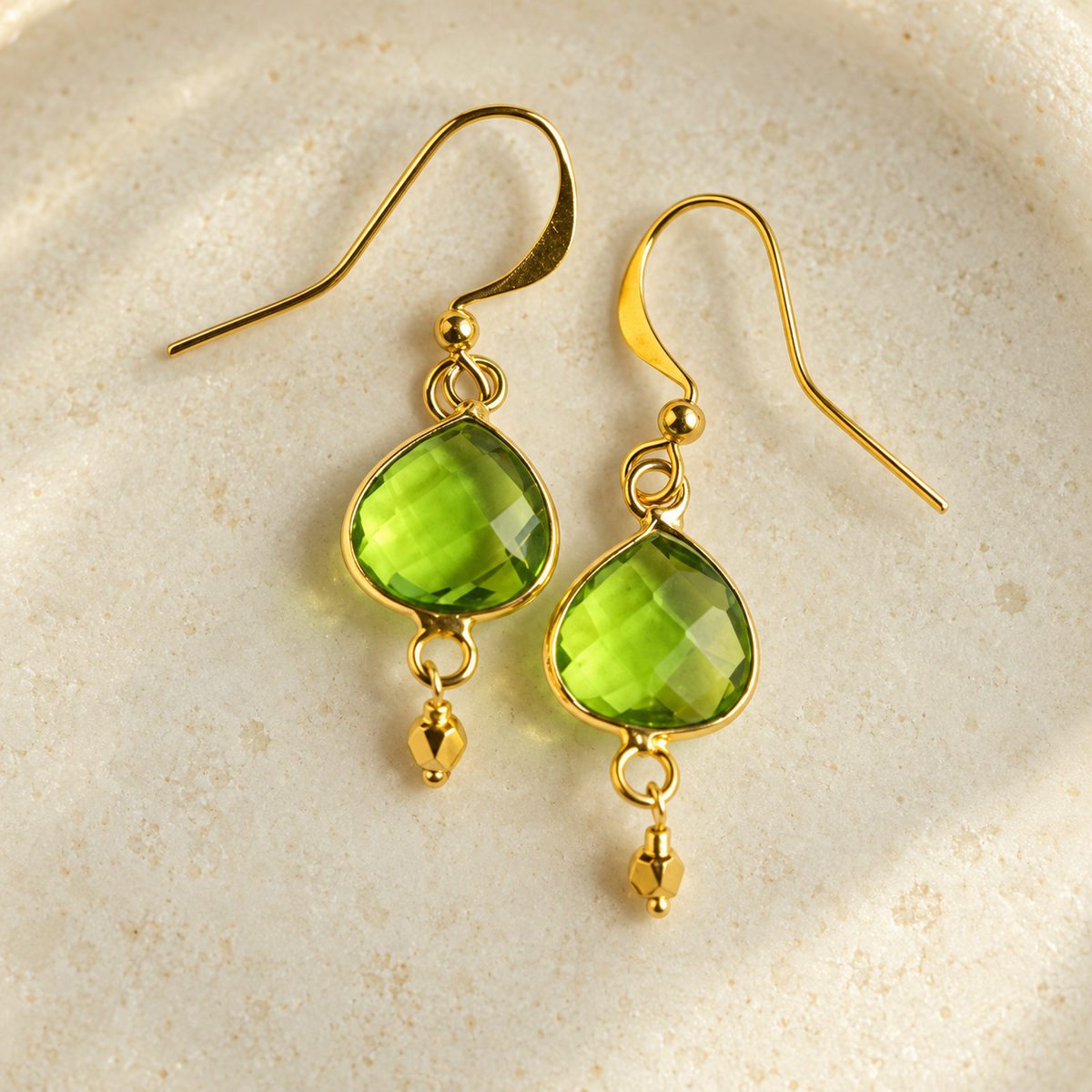 Peridot Ballet Drops: a pair of faceted green gemstone earrings with gold hooks and small dangling gold accents. AI-styled closeup; original product photographs remain in the gallery.