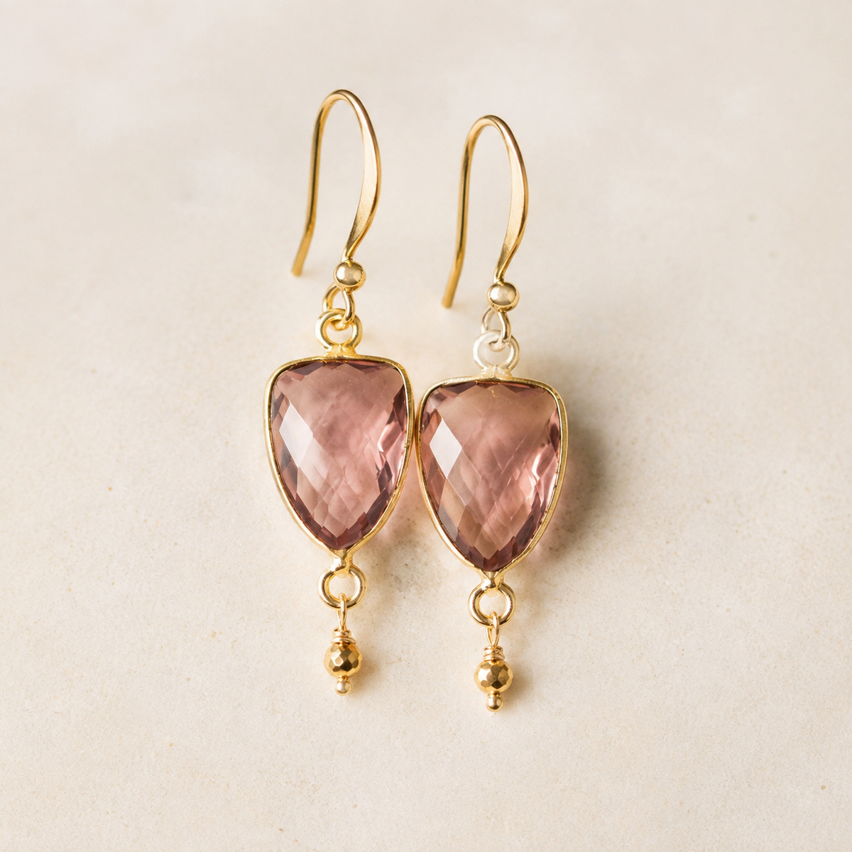 The Isla Drops in Rhodolite Garnet — refined close-up of rose-mauve stones and gold-plated silver hooks.