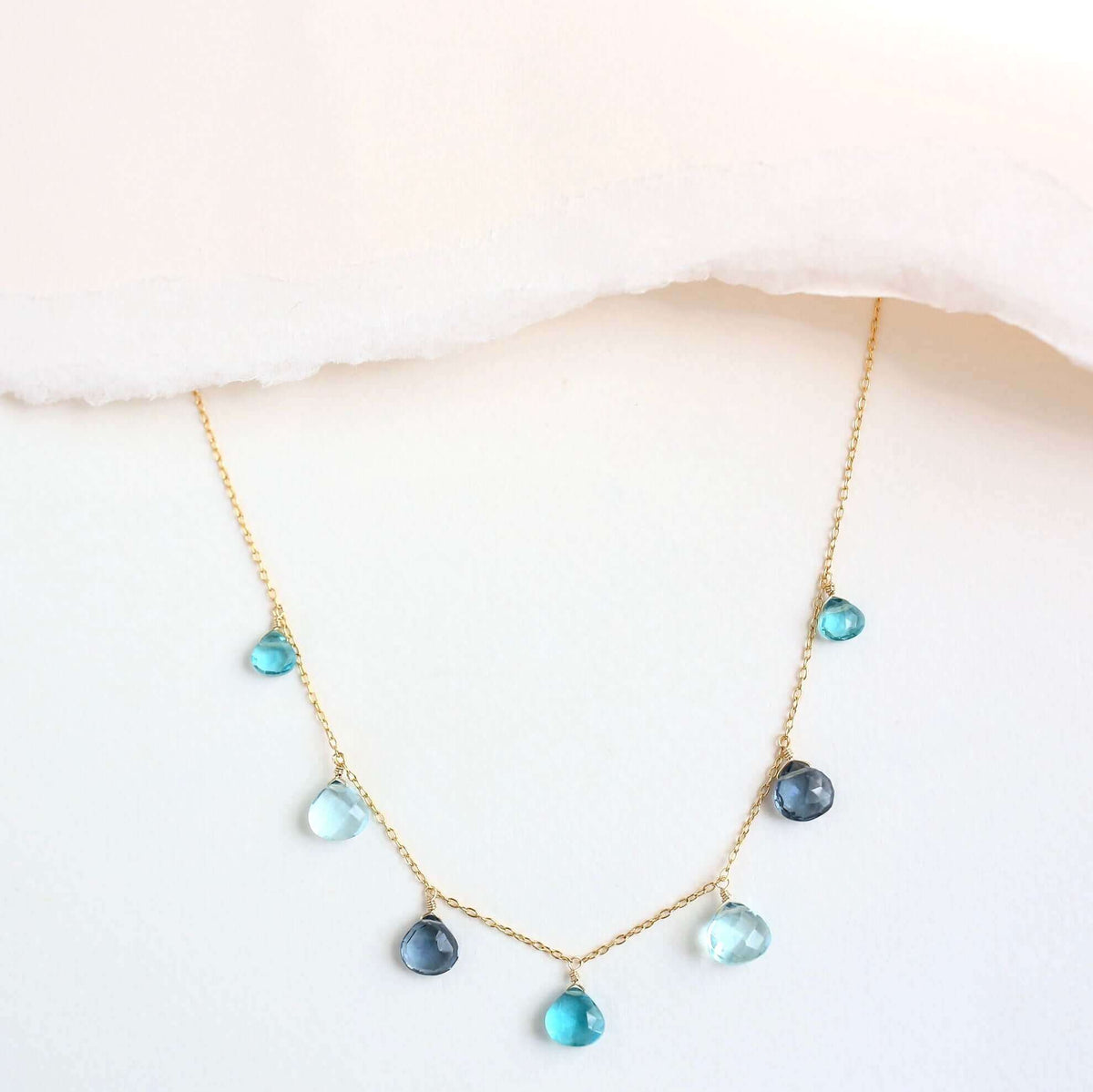 The Azzurra Necklace in gold, showing the arrangement of blue gemstone drops along the chain.
